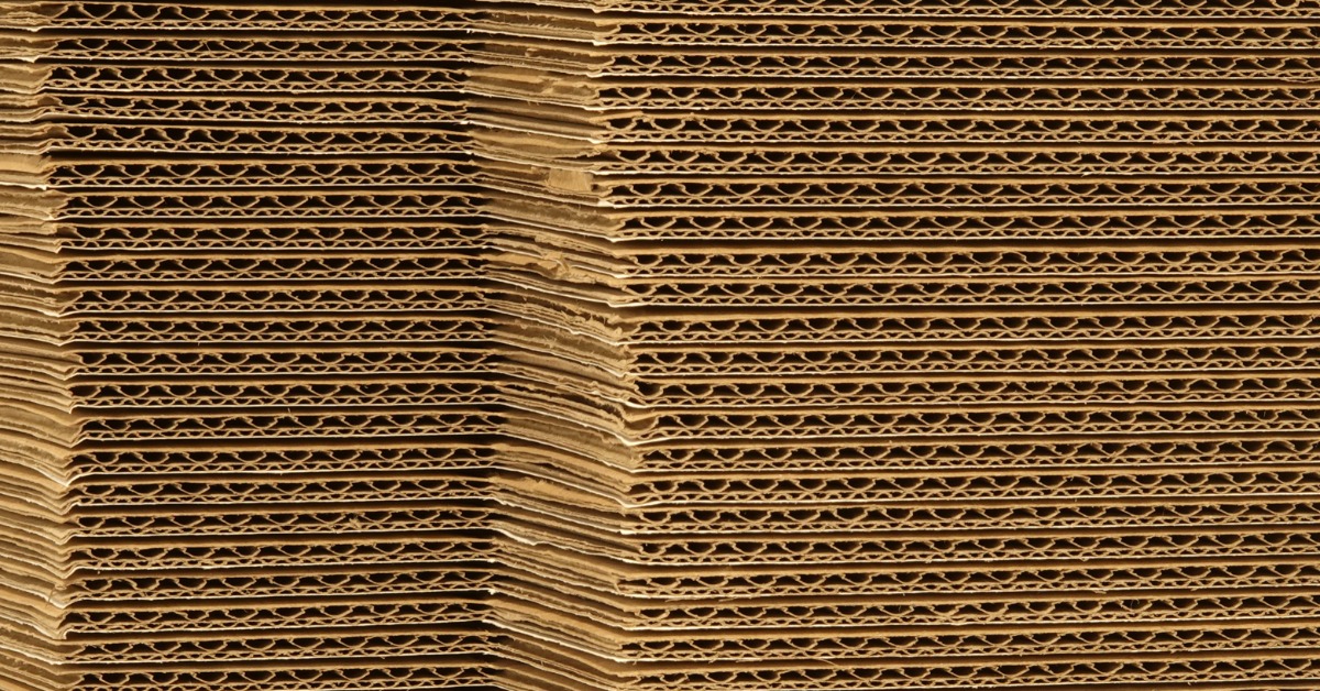 Large stacks of corrugated box cartons. The layered boxes feature a double-wall configuration with two fluted layers.