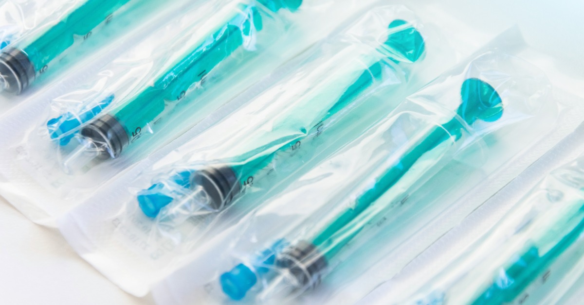 A close-up of multiple green syringes inside individual blister packaging made with clear plastic.