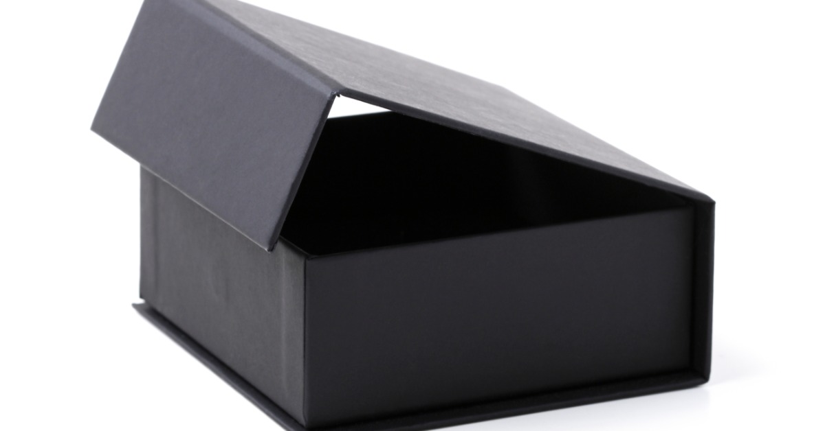 A close-up of a small, black, empty box with a lifted top attached from the back side, placed on a white surface.